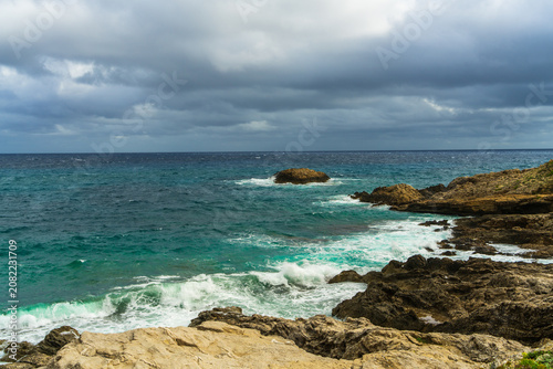 Blue Mediterranean Sea washing rocky shoreline in Mallorca, Spain. Scenic coastal landscape, crystal clear water, natural beauty, summer travel and seaside destination concept.