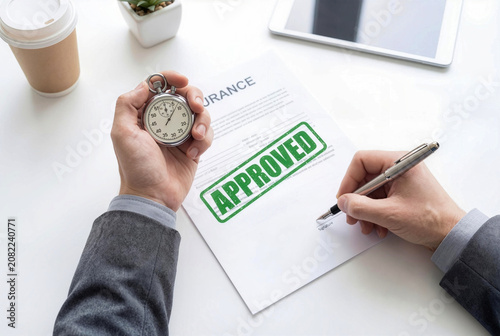 Businessman Signing Approved Insurance Contract Document While Holding Stopwatch