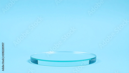 Empty crystal-clear glass podium against solid light blue background for a minimalist product presentation. Mock-up. Close-up.