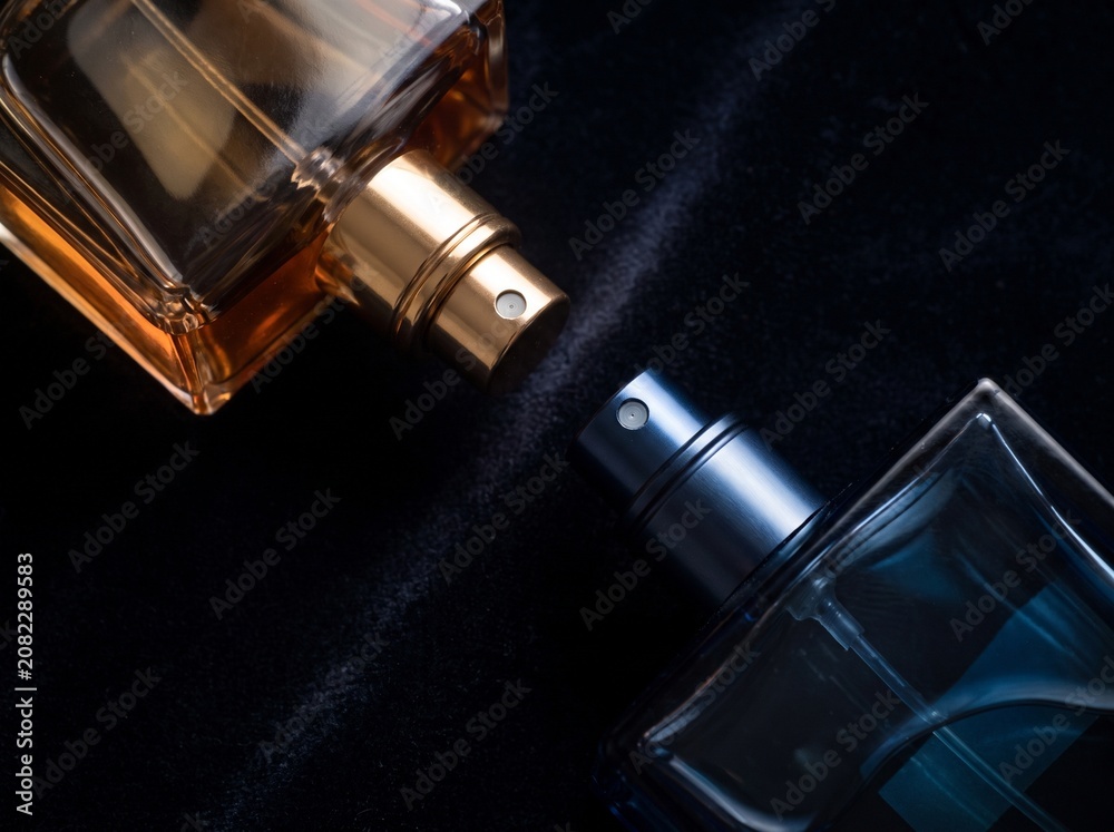 Obraz premium Two luxury glass perfume spray bottles on black velvet background with fragrance