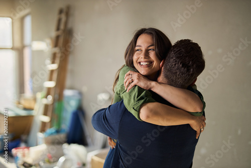 Canvastavla Happy young couple embracing on a residential construction site, celebrating their new apartment renovation