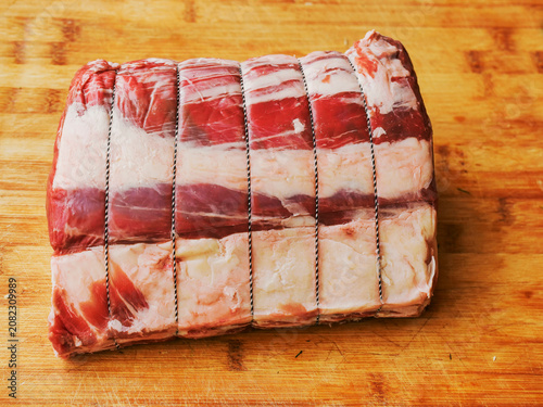 Huge carvery rib roast on the bone is on a wooden cutting board. Butcher craft and skill product. Top quality beef meat with high value and price tag due to premium cut and complicated production.