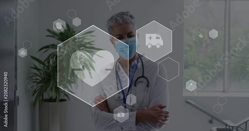 On start senior physician standing arms crossed, hex overlays pulsing heart highlighting vitals