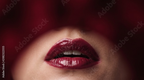 Macro Photo of Glossy Dark Red Lips with Soft Rim Lighting, Minimalist Blurred Red Background and Headline Text Space