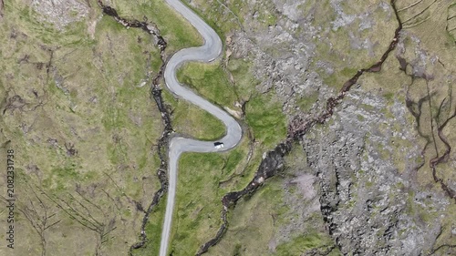 Drone shot of vehicle driving on serpentine switchback road in Faroe Islands