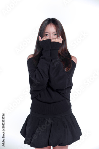 Portrait of a playful young Asian woman covering her face with her sweater sleeves