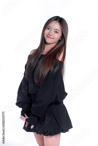 Portrait of a smiling young Asian woman in casual black clothing standing with clasped hands