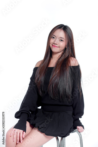 Portrait of a smiling young Asian woman sitting and looking at the camera