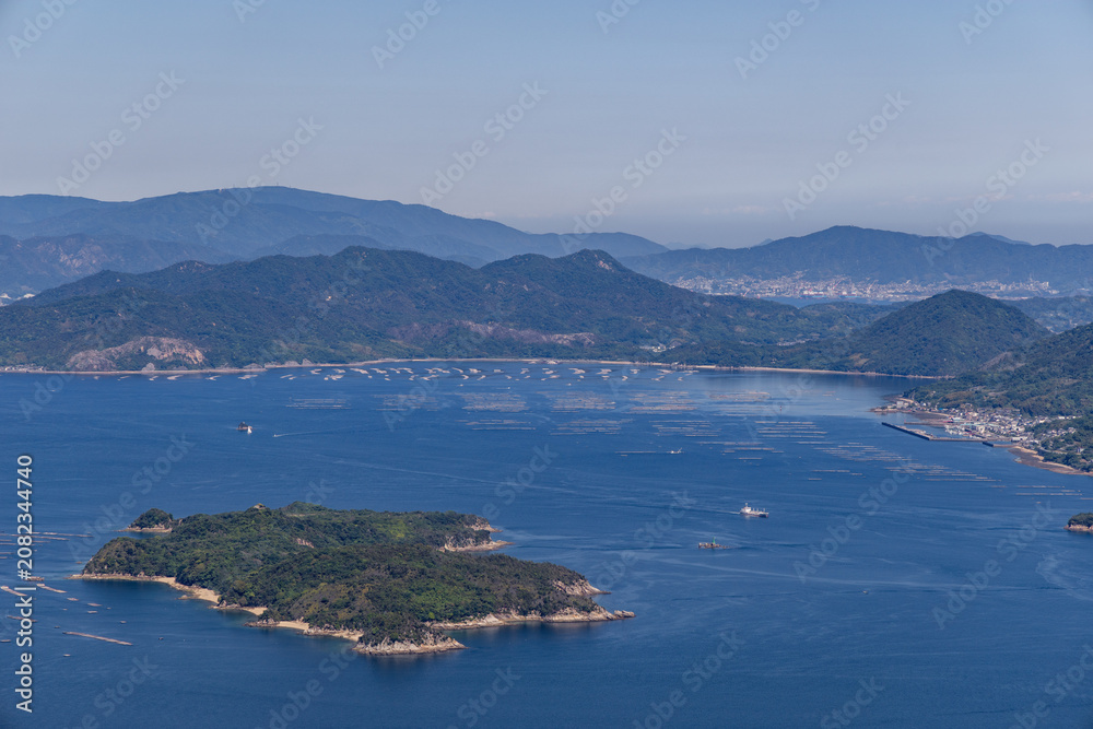 Fototapeta premium view from mount Misen of the Seto inland sea bay, with floating oyster farms beneath a blue sky and in bright sunshine