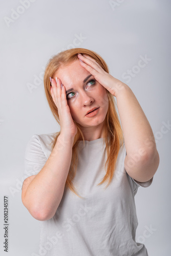 Young woman experiencing intense headache, holding her head with hands while looking up, representing concepts of stress, worry, and emotional exhaustion