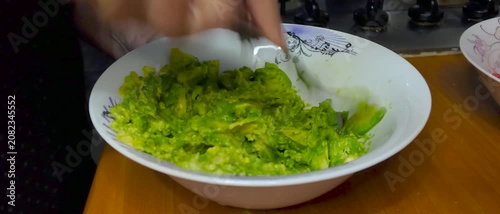Close Up of Hands Mashing Fresh Ripe Avocado with Fork in Bowl During Home Kitchen Food and Meal Preparation for Homemade chilean version of Sandwiches Hot Dogs (completo italiano) a Healthy Recipes