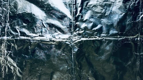 textured tinfoil background with abstract metallic crinkles gleaming under stark cinematic lighting