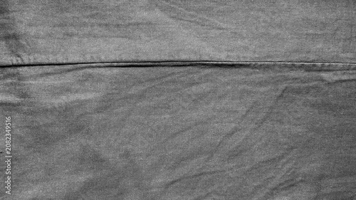 textured dark grey denim fabric showing detailed weave pattern and central stitched seam in a macro close up