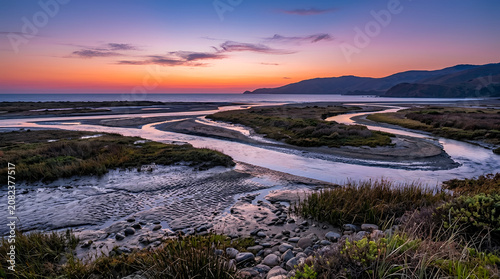 Serene Sunset Over Coastal Estuary Wetlands Featuring Winding Tidal Channels and Distant Rolling Hills at Golden Hour