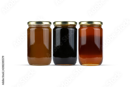 Three Glass Jars of Honey with Different Shades on White Background