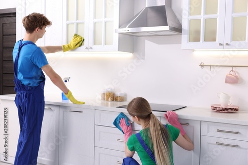 Fotografie Teenage workers cleaning cabinets in kitchen. Part-time job