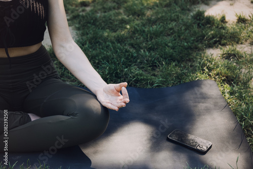 Фотография Woman sits in meditation posture on mat outdoors on grass