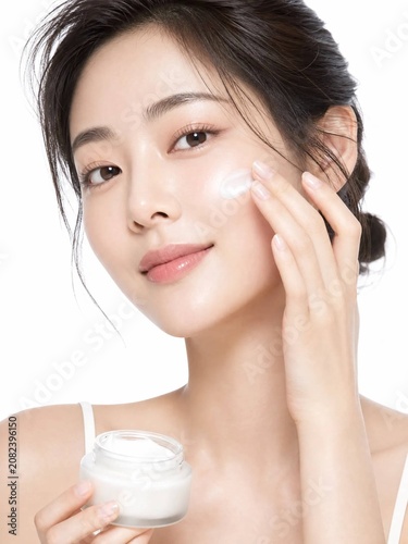 young woman applying cream on her face
