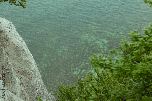 Obraz na plátně Aerial view of rocky cliff edge overlooking clear turquoise water with visible u