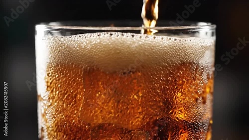 Slow push-in reveals dark carbonated soda pouring into a glass with perfect ice cubes, effervescent bubbles popping on the surface under high-contrast commercial lighting for a refreshing aesthetic.