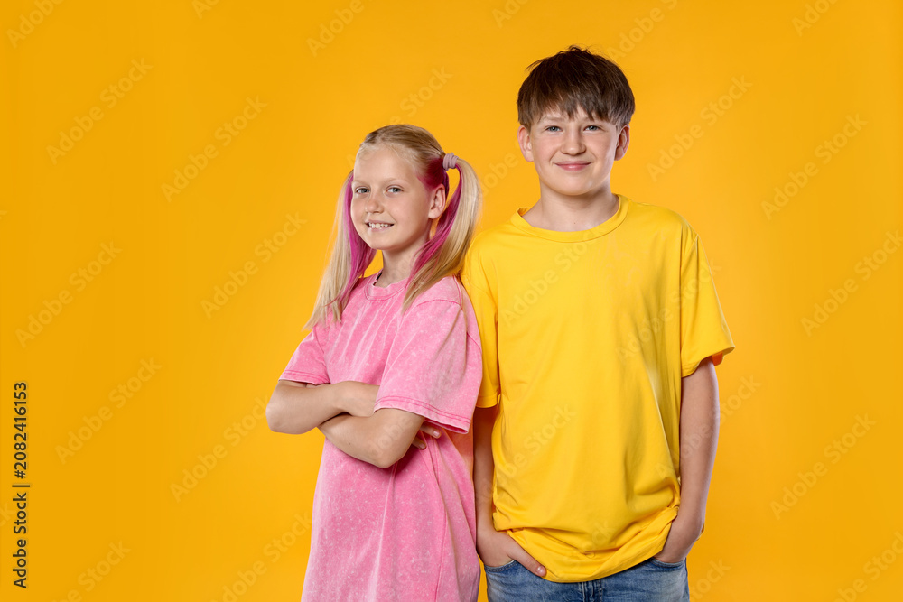 Fototapeta premium Portrait of brother and sister on orange background