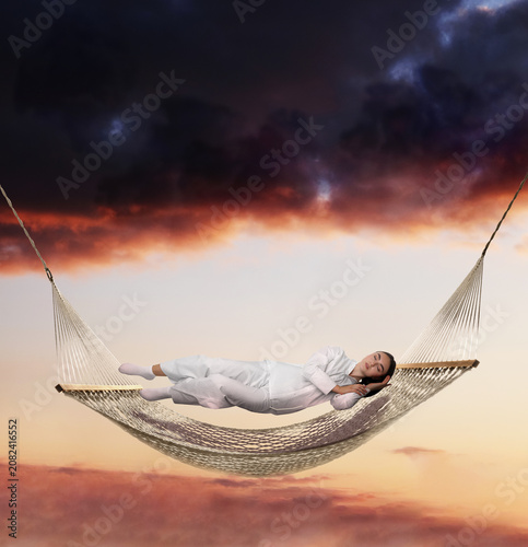 Bild auf Leinwand Young sleeping woman levitating above hammock against bright sky