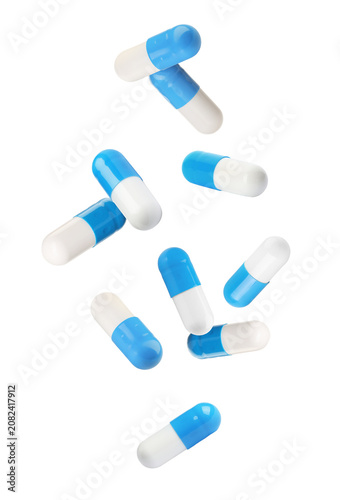 Blue and white capsules falling against transparent background. Pills