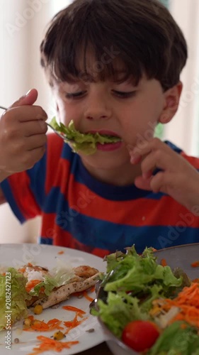 Young boy enjoying leafy salad during family meal, highlighting healthy nutrition, wholesome eating and everyday childhood wellbeing