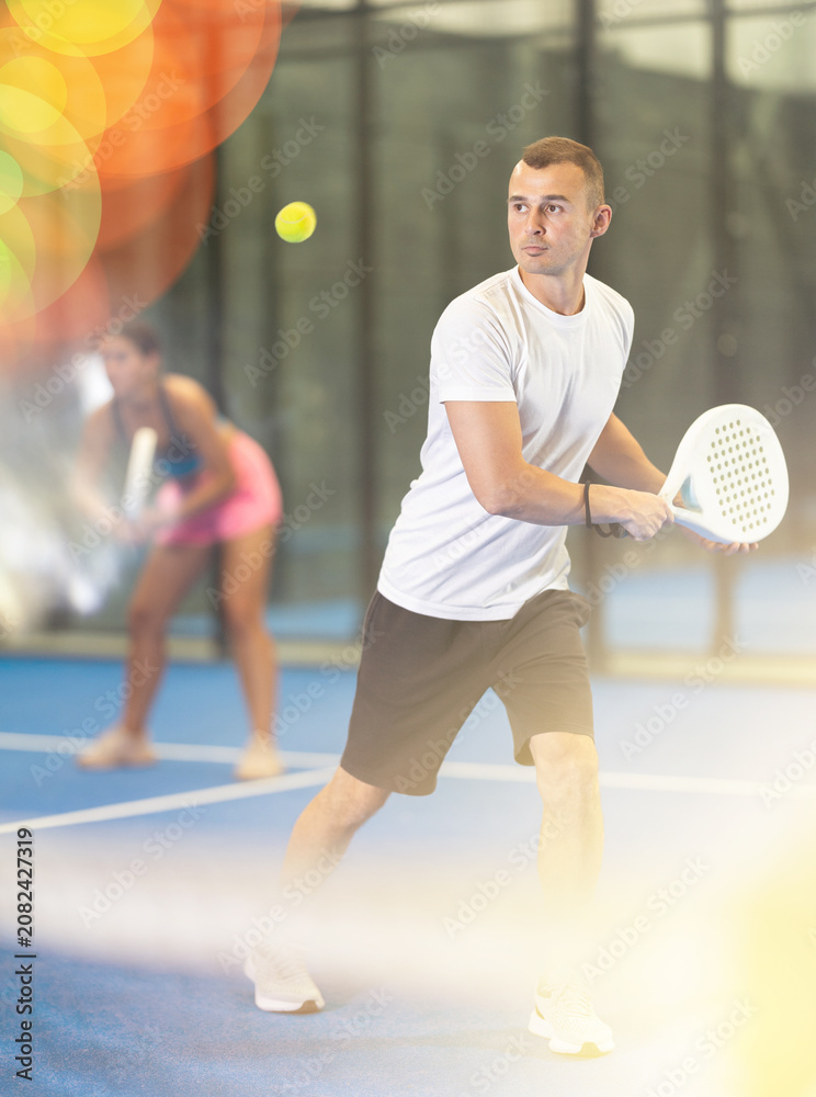Fototapeta premium Padel game - girl with partners plays on the tennis court