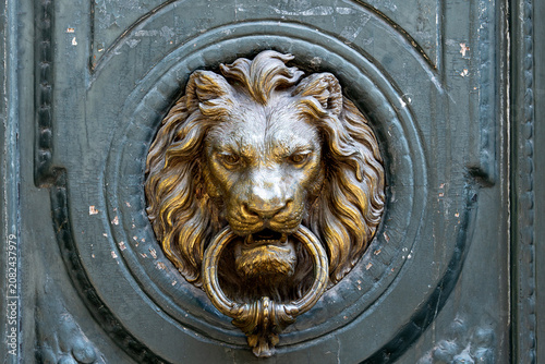Close-up of an ornate antique lion head door knocker on a weathered historic door, showcasing classic architecture, craftsmanship, and timeless decorative design.