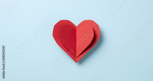 Layered red paper heart cutout on a soft pastel blue background for Valentines Day