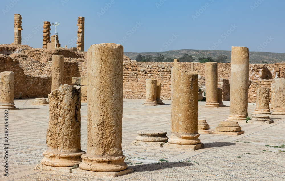 Obraz premium Remains of ancient weathered stone columns rising from mosaic floors at ruins of Grand Baths of Sufetula on sunny spring day, Tunisia