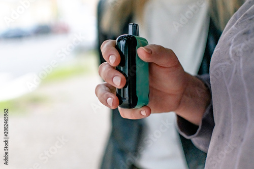 Fotografía In his hands is a compact gadget - an electronic cigarette or vape in turquoise (mint) color with a black mouthpiece or top panel