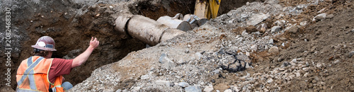 Fotografía Excavator digging a deep narrow ditch in the dirt to work on underground utiliti