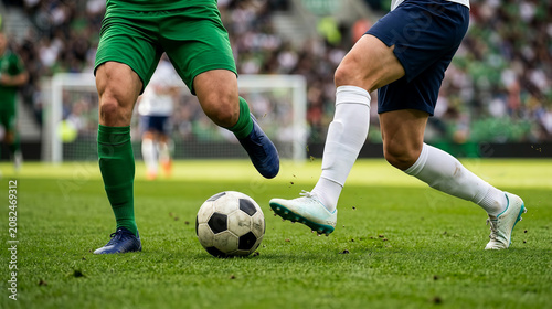 Action shot of soccer players battling for ball on stadium turf with football