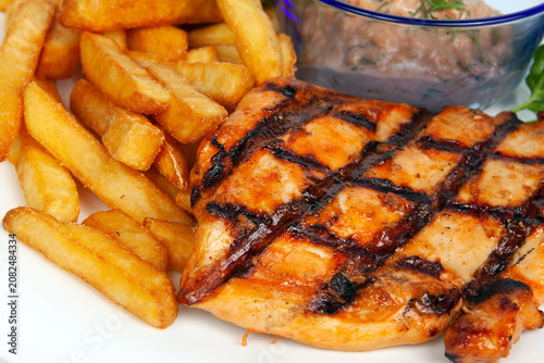 Closeups of a grilled chicken or pork neck steak served with crispy golden french fries. Barbecue meat dish, hot dinner food meal, savory restaurant culinary catering. BBQ.