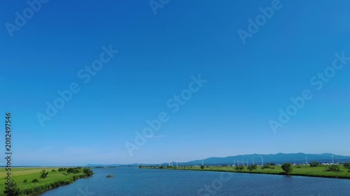 【4K】津軽大橋から望む岩木川と遠く広がる小泊岬：初夏の青空と瑞々しい緑。青森の豊かな大自然を捉えたランドスケープ移動映像素材　[4K] Scenic View of Iwaki River and Distant Cape Kodomari from Tsugaru Bridge: Summer Landscape in Aomori Japan 撮影日：20260624-1

