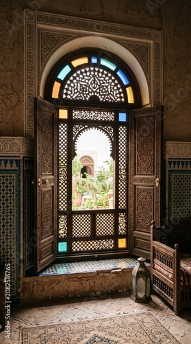 Ornate Moroccan wooden window opening to a riad garden
