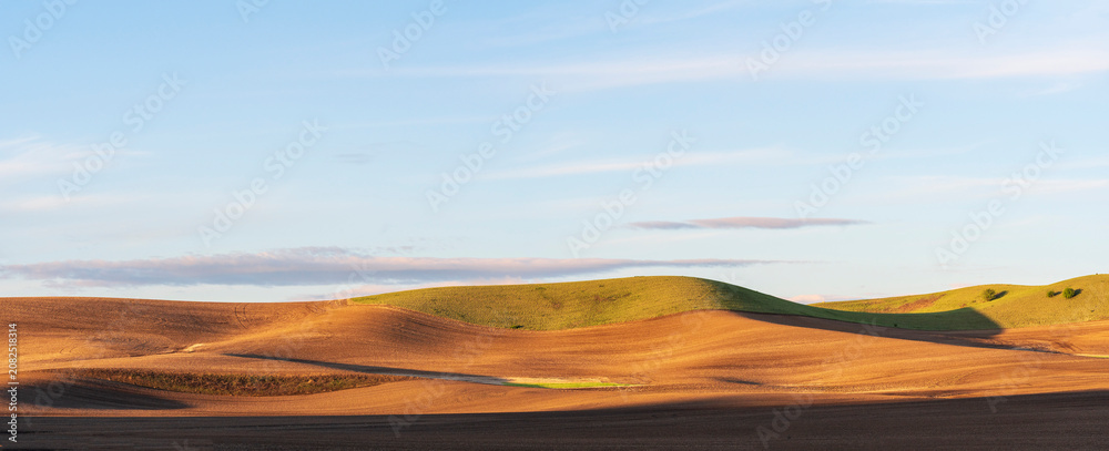 Fototapeta premium dirt fields with rolling hills with light on the hill