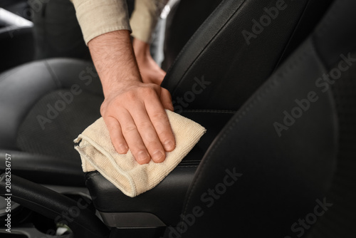 Obraz na plátně Person cleaning black leather car armrest with cloth