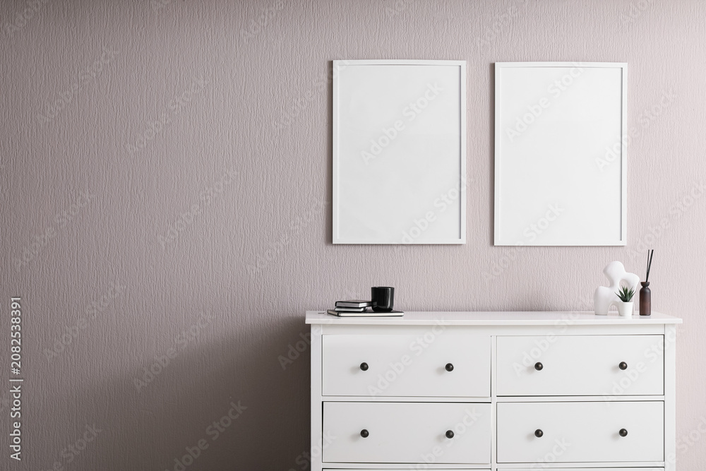 Fototapeta premium Minimalist interior with white dresser and blank frames