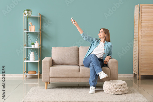 Young woman sitting on sofa...