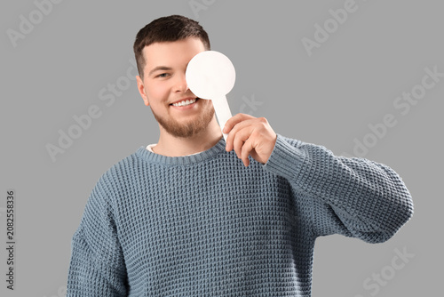 Young man with eye occluder on grey background