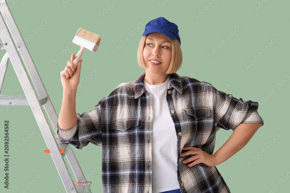 Naklejka premium Female decorator with ladder and brush on green background