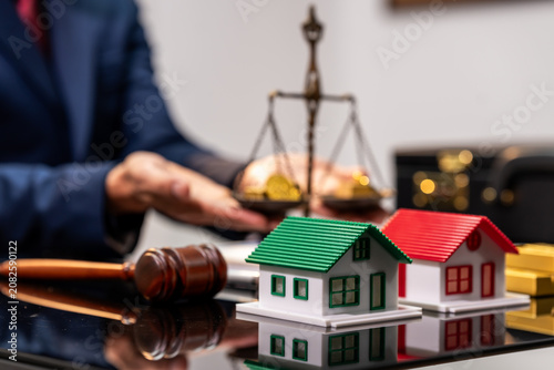 Model houses with gavel and scales on a desk, showing property law, home ownership, and real estate dispute concept