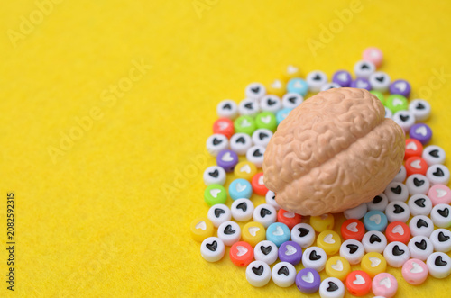 Konstfotografi Brain model resting on colorful heart shapes representing psychological wellness