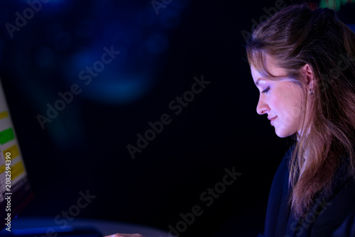 Fotografia Two diverse businesswomen working late at trading desks with warm screen light o