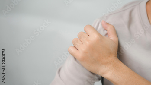 Close-up of a person holding a painful shoulder due to muscle strain, joint injury, or overuse. Healthcare concept highlighting shoulder pain, rehabilitation, physical therapy, recovery.