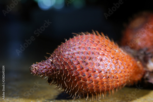 фотографія Close up of reddish brown tropical fruit with rough, spiky skin resting on surfa