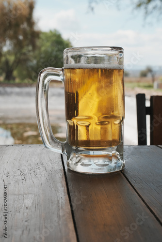 Cold Glass Mug of Beer on a Wooden Table Outdoors